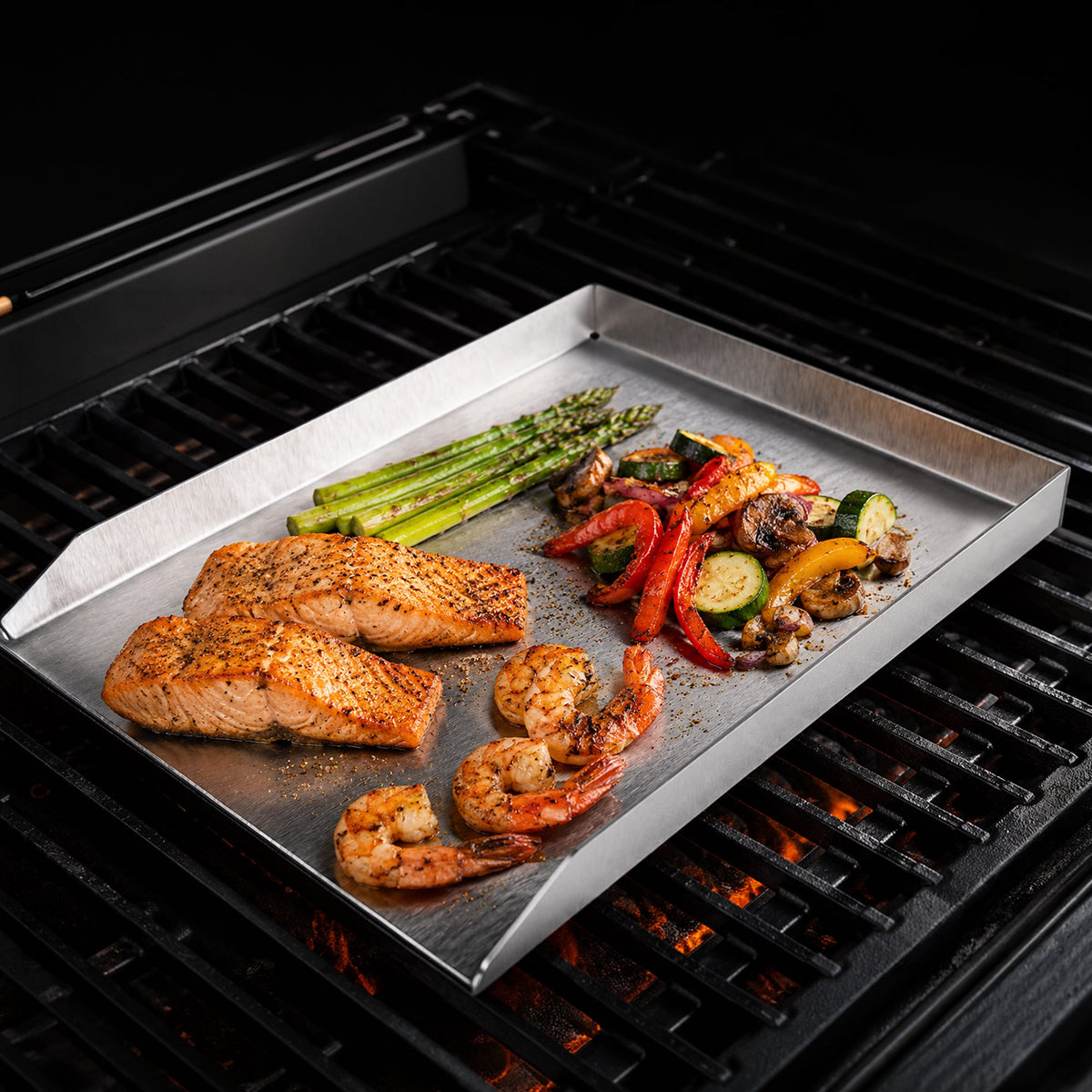 Plancha aus Edelstahl mit Lachs, Garnelen, Spargel und Paprika auf dem Rost eines Gasgrills